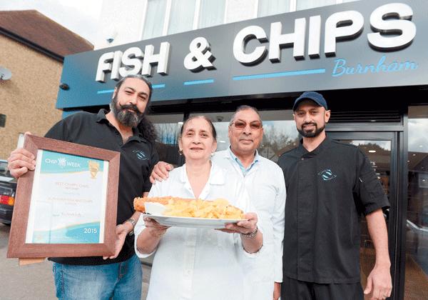 The Burnham Fish and Chips family outside the shop holding a plate of fish and chips and an award
